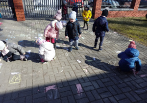 Dzieci malują kolorowymi kredami płyty chodnika